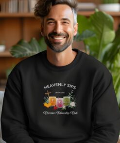 Black sweatshirt with Three faith-inspired juice glasses: Joyful Juice (orange with a cross), Blessed Berry (pink with a dove), and Graceful Green (green with a fish).