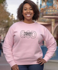 Woman wearing a light Pink sweatshirt with Trust in God on front Trust in God