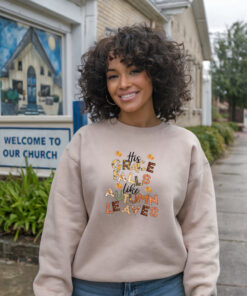 a smiling African American-woman wearing a sand colored Gildian 1800 sweatshirt His Grace Falls Like Autumn Leaves