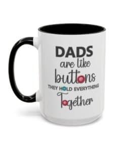 15 oz White ceramic mug with black rim and handle featuring the phrase “Dads are like buttons they hold everything together” left view