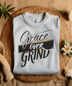 Ash Colored Gildan 5000 Grace Over Grind t-shirt features bold calligraphy, gold and black brushstrokes, and an inspirational Christian faith message