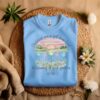 Blue Flat fold Children Are a Gift From God Floral Christian T-Shirt featuring a watercolor sunrise, handprint flowers, and faith-based quote.