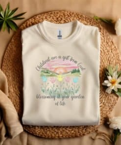 Sand colored flat fold Children Are a Gift From God Floral Christian T-Shirt featuring a watercolor sunrise, handprint flowers, and faith-based quote.