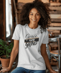Ash Colored Gildan 5000 Grace Over Grind t-shirt features bold calligraphy, gold and black brushstrokes, and an inspirational Christian faith message