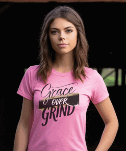 Pink Gildan 5000 Grace Over Grind t-shirt features bold calligraphy, gold and black brushstrokes, and an inspirational Christian faith message